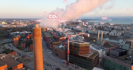 Smoking Industrial chimney with animated CO2 icons.City in background. Aerial