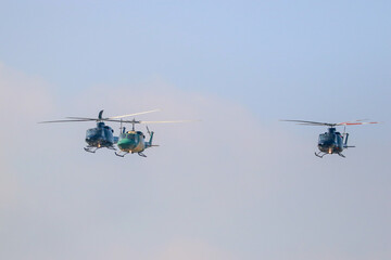 bell 212 rescue helicopter in camouflage colours and  black bell 412 helicopters are flying formation with national flag of sri lanka