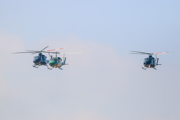 bell 212 rescue helicopter in camouflage colours and  black bell 412 helicopters are flying formation with national flag of sri lanka