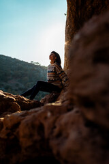 happy woman in the mountains. girl resting sitting on a stone in the mountains. trekking and hiking. concept of sports and healthy lifestyle.