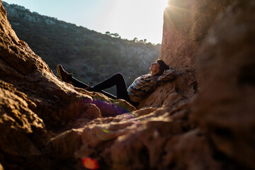 happy woman in the mountains. girl resting sitting on a stone in the mountains. trekking and hiking. concept of sports and healthy lifestyle.