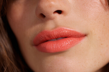 Close-up of soft coral lips showcasing natural beauty and flawless skin in bright, natural light for a fresh makeup look