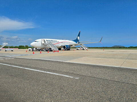 Zihuatanejo, Guerrero, Mexico - Jun 17, 2025: Ixtapa Zihuatanejo International Airport, an Aeromexico plane parked on an airport tarmac with stairs and cones under a clear blue sky