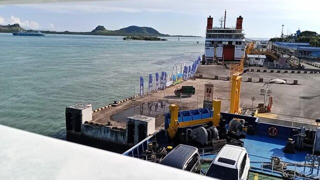Ferry docked at a port with cars onboard and sea view in the background