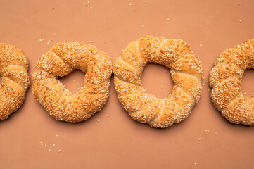 Simit or gevrek, round bagel with sesame seeds on brown background top view. Creative layout with food. Traditional Turkish pastry. Delicious fresh homemade pastry, bakery product. Bagel mockup