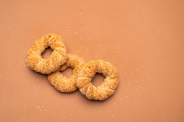 Simit or gevrek, round bagel with sesame seeds on brown background top view. Creative layout with...