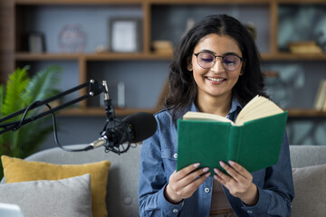 Close-up photo of a young Indian girl at home, sitting on the couch and reading into a microphone...