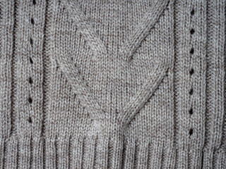 Neutral gray wool and cashmere knitwear with braid cable stitch knitted pattern, cozy winter textile background.