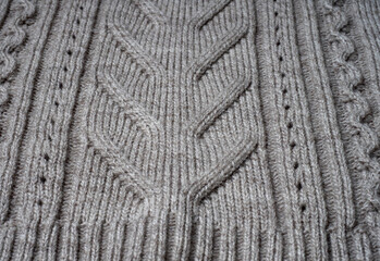 Neutral gray wool and cashmere knitwear with braid cable stitch knitted pattern, cozy winter textile background.