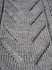 Neutral gray wool and cashmere knitwear with braid cable stitch knitted pattern, cozy winter textile background.