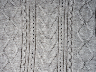 Neutral gray wool and cashmere knitwear with braid cable stitch knitted pattern, cozy winter textile background.