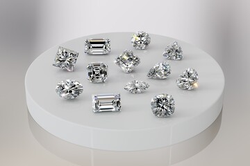 Variously cut diamonds: round brilliant, cushion, heart, asscher, radiant, emerald, baguette, oval, pear, marquise, trilliant, on white tray on white background.