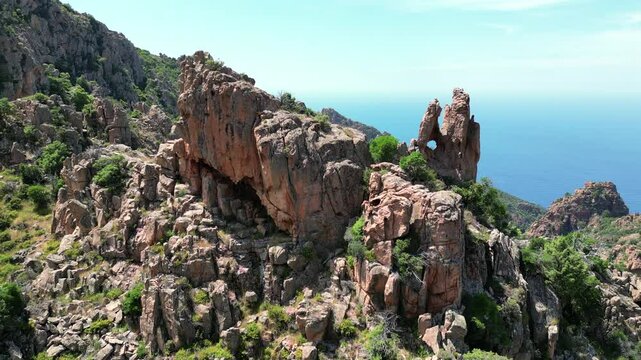 Aerial view circling a dramatic rock formation at the Calanches de Piana, a UNESCO world heritage site, on the coast of the Mediterranean island of Corsica