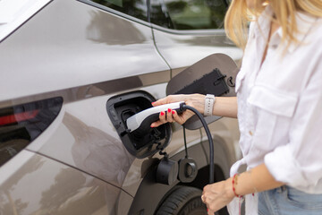 Businesswoman charging electric car at charging station
