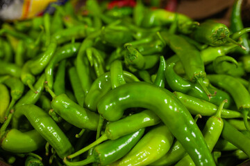 A vibrant bounty of fresh, glossy green chilies, piled high, showcasing their spicy allure and healthy freshness, perfect for culinary and food-related themes
