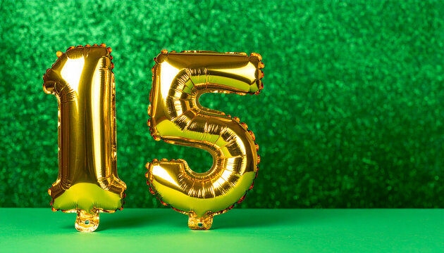 Banner with number 15 golden foil balloon. Anniversary celebration. Green backdrop with bokeh.
