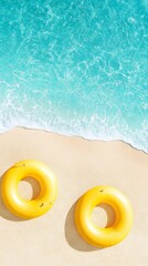 Naklejka premium Two vibrant yellow inflatable rings resting on a sandy beach, with gentle waves lapping at the shore, creating a serene summer atmosphere for relaxation and fun