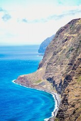 Steep ocean cliffs and deep blue waters on the coast of Madeira