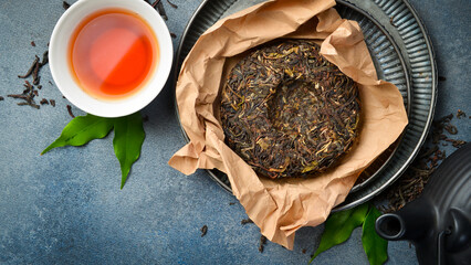 Unpacked dry pressed pu erh tea and a cup of tea. On a gray stone background. Top view.