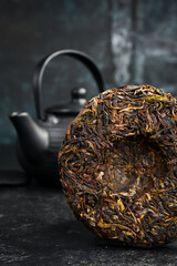 Fermented Pu-erh tea disc and ceramic teapot for brewing tea. Chinese traditional drink.