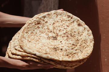 Hands holding moroccan amazigh bread known as Tafarnout bread or tafournout bread