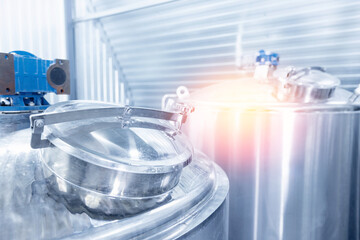 Stainless steel brewing tanks in modern beer factory, sunlight