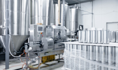 Modern beer factory interior with stainless steel tanks and aluminum cans