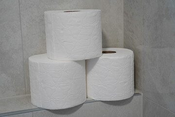 Toilet paper rolls stacked in a tower shape in a clean bathroom.