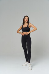 Fit brunette model showcases athletic form in stylish workout attire in a studio setting