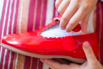 new pair of patent leather shoes, Little girl excitedly putting on bright red shoes, learning to...