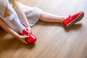 new pair of patent leather shoes, Little girl excitedly putting on bright red shoes, learning to...