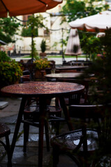 A beautiful street restaurant with vintage wooden tables and umbrellas during the rain.