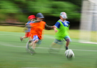 little four -year-old boys plays football at a sports school .Blur.
