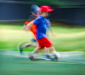 little four -year-old boys plays football at a sports school .Blur.