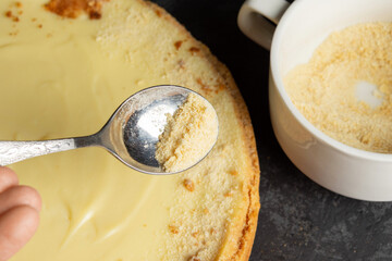 Homemade classic cheesecake on dark background. Decorating delicious cake with cookie crumbs.