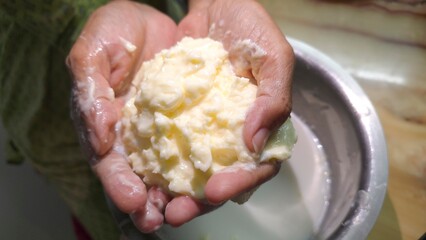 Indian mother making traditional Indian white butter, or safed makkhan after churning creamy curd. Soft and tasty dallop of makkhan ball