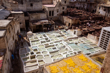 An elevated, wide-angle view captures the bustling Chouara Tannery in Fes, Morocco, with numerous...