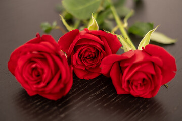 Closeup view of three Red roses on a black table. Anniversary, Valentine's day, emotions and love