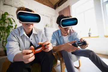 Father and son, enjoy virtual reality gaming with controllers in a bright living room. Concept of immersive entertainment and modern technology.