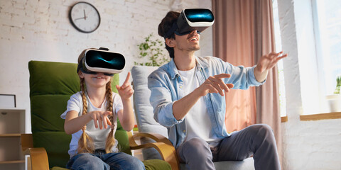 A middle-aged father and his young daughter enjoy a virtual reality experience in a modern living room. Concept of family bonding through technology.