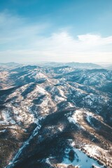 Aerial view of a snowy mountain range under a blue sky