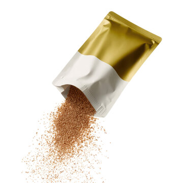 Gold and white foil pouch torn open with fine brown granules spilling in textured scatter mid-fall, isolated transparent background