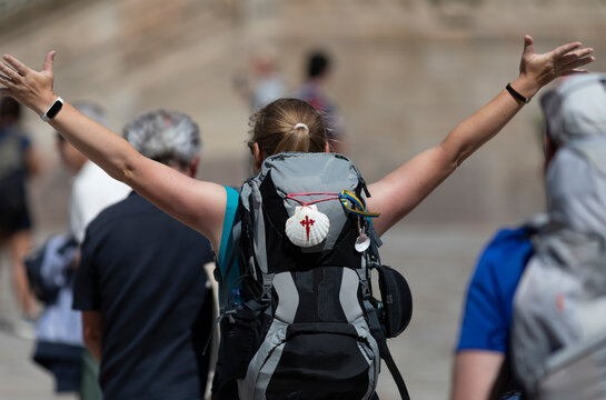A pilgrim celebrates her arrival at Plaza do Obradoiro in Santiago de Compostela after completing the Camino de Santiago.