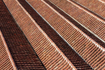 An overhead view showcases the intricate pattern of a vibrant terracotta tile roof, with rows of half-round tiles creating strong diagonal lines and shadows.