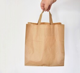 Kraft bag in hand on white background. Eco-packaging