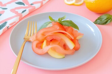 vegetable salad with basil leaves on a light gray plate, accompanied by a golden fork