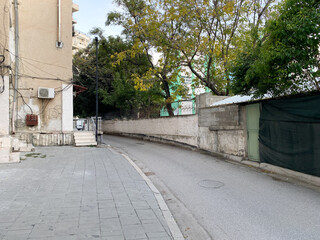 Urban scenery from Albania showing modest houses, roadside greenery, and electric poles. Evokes regional charm. Great for stories about local living or Balkan architecture.