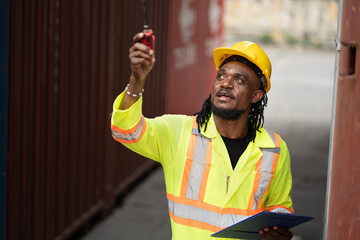 African worker working with use clipboard checking container at container site	