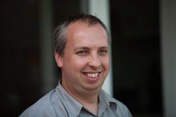 A cheerful man is smiling warmly, captured beautifully in a bright and relaxed environment that...