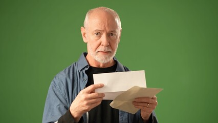 POV of mature senior man with a beard gestures thoughtfully while standing against a solid green...